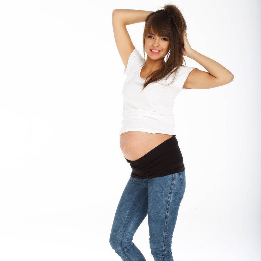 Fascia addominale nera in tencel. La donna indossa jeans e top bianco. Sorride.