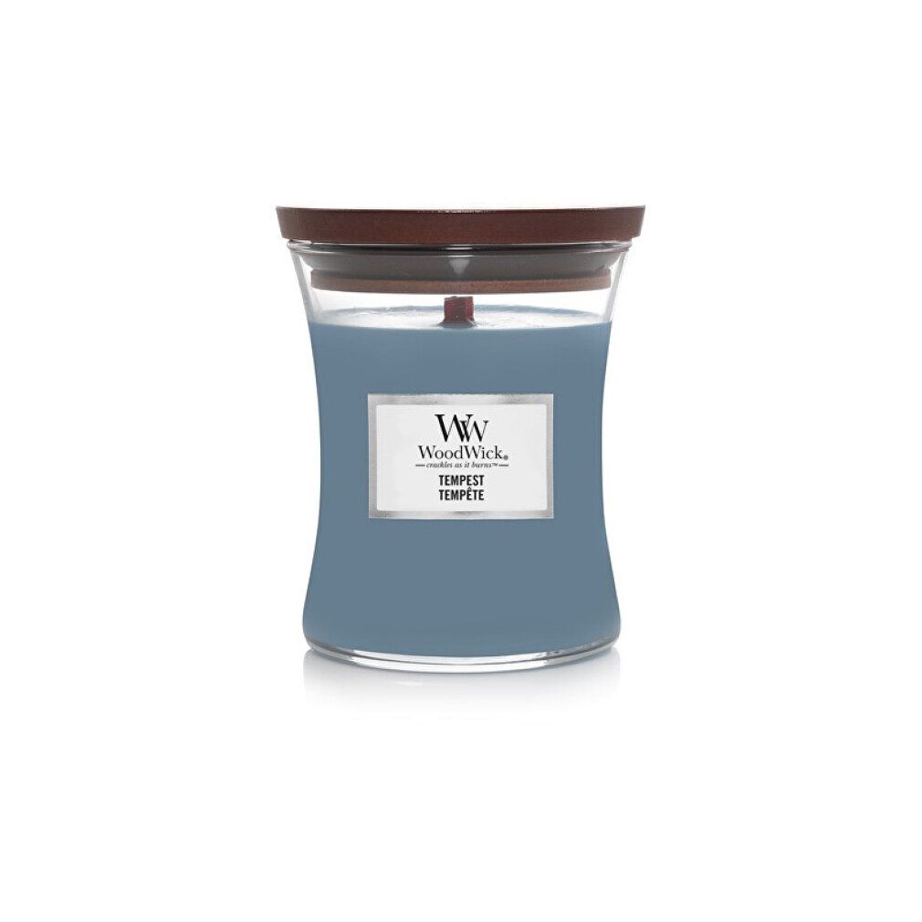 Candela a clessidra con coperchio in legno. Cera blu, etichetta rettangolare con logo e testo. Stoppino in legno visibile.