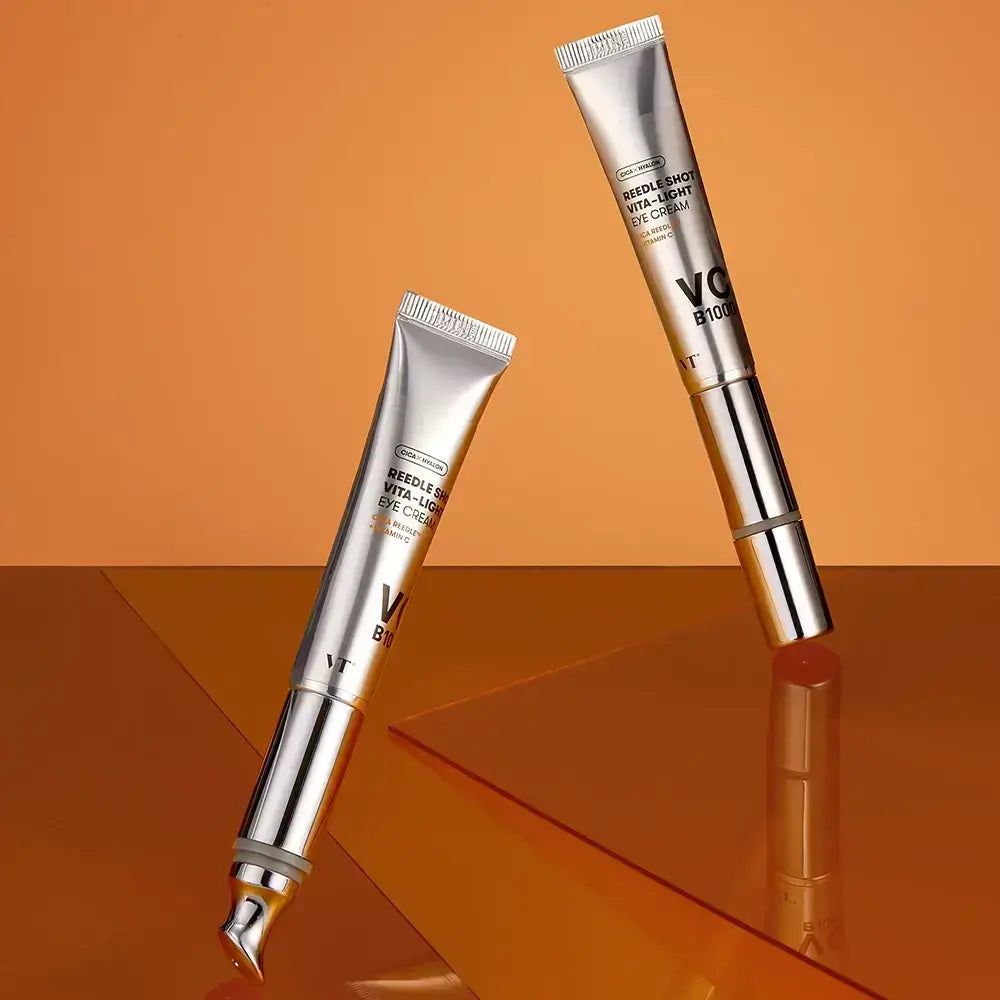 Due tubi di VT Cosmetics Reedle Shot Vita-Light Eye Cream su sfondo arancione.