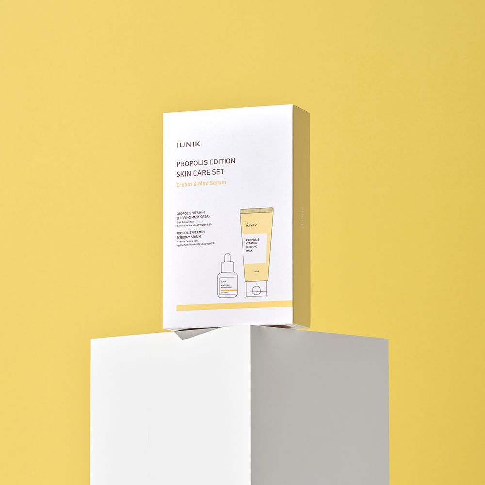 Scatola bianca iUNIK Propolis Edition Skin Care Set con immagini dei prodotti. Su piedistallo bianco, sfondo giallo.