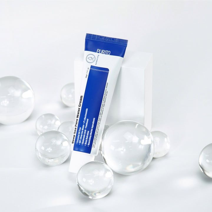 Tubo di crema su piedistallo bianco. Biglie di vetro. Testo: Deep Sea Pure Water Cream. Marchio PURITO. Confezione blu e bianca.