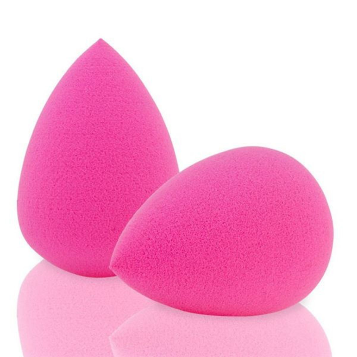 Due spugnette per il trucco rosa acceso a forma di goccia, su una superficie riflettente.
