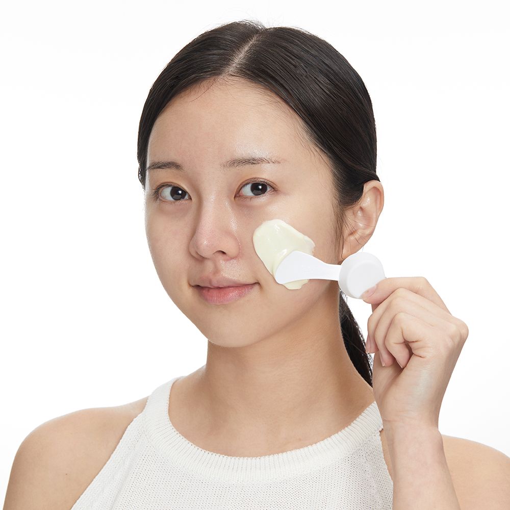 Una donna applica una maschera Modeling Pack sul viso con una spatola.