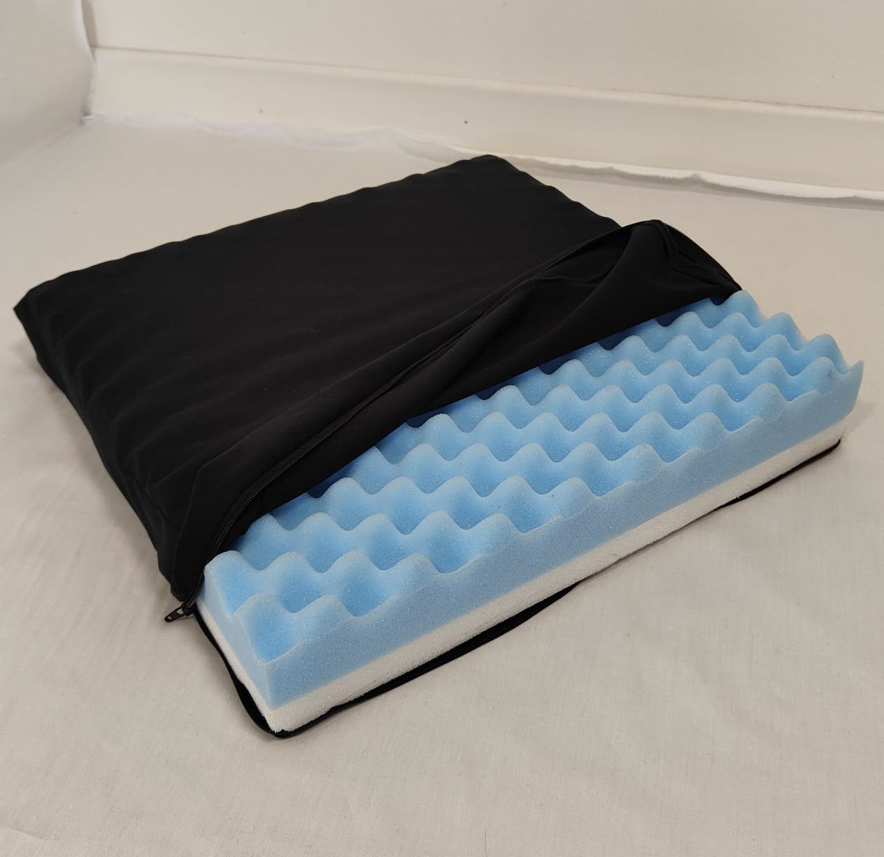 Rivestimento nero parzialmente aperto. Interno in schiuma blu ondulata. Forma rettangolare.