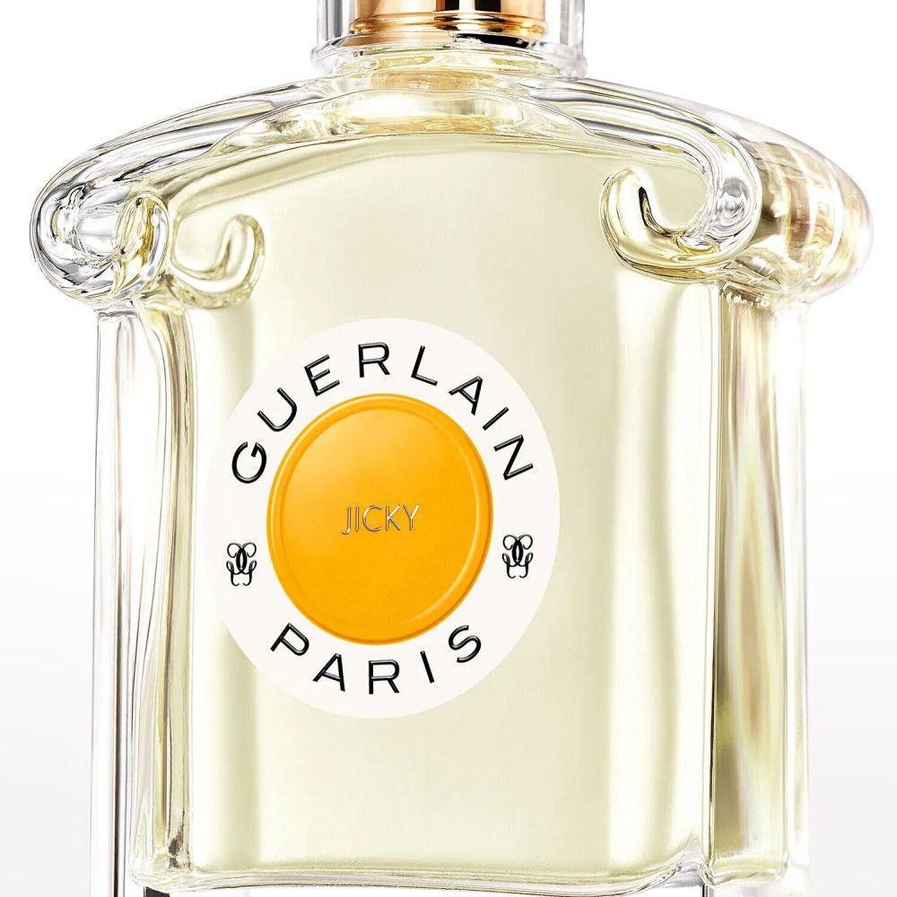 Flacone di profumo con etichetta rotonda. Scritta: GUERLAIN PARIS, JICKY. Liquido giallo visibile.
