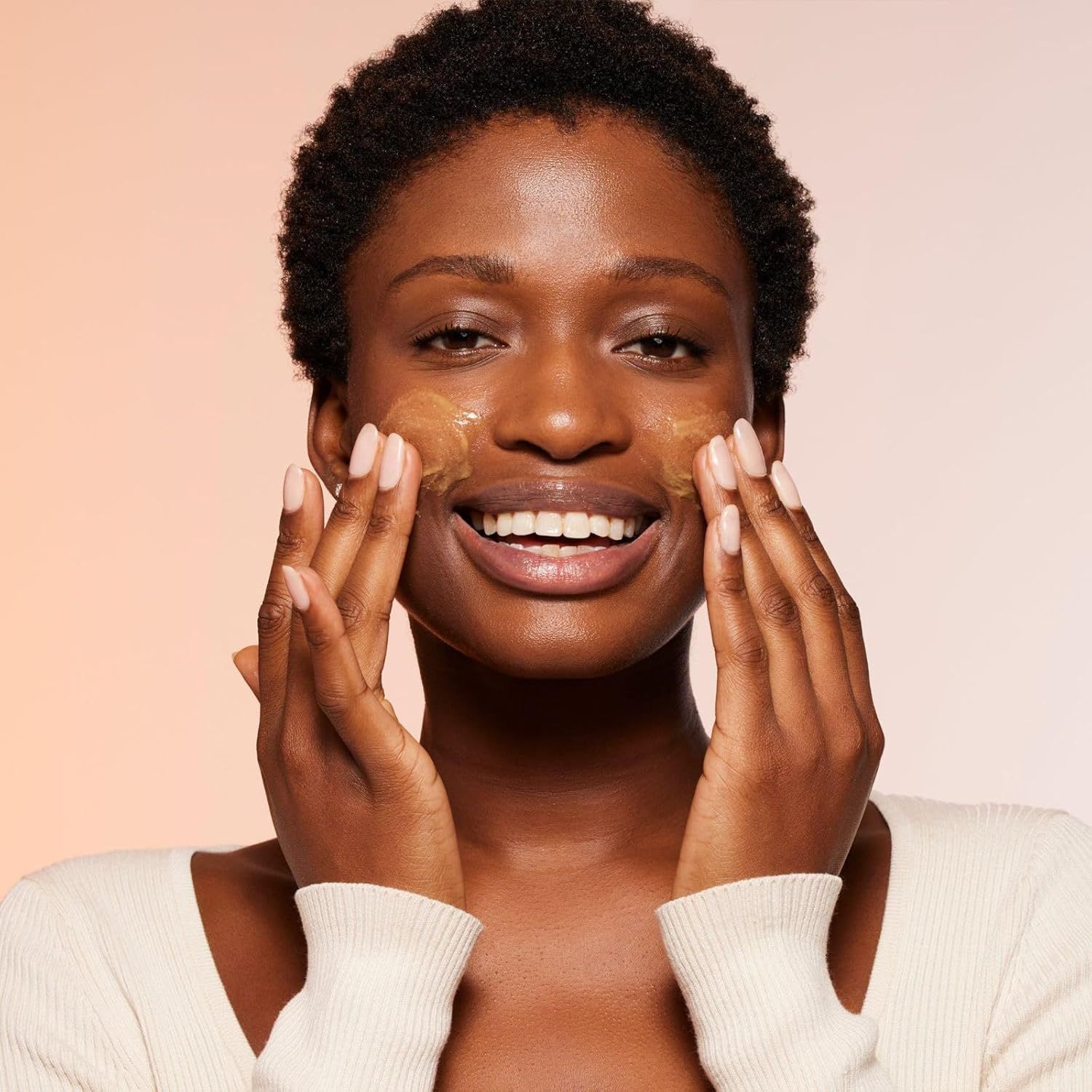 Donna con prodotto sul viso. Sostanza giallastra sulle guance. La donna sorride.