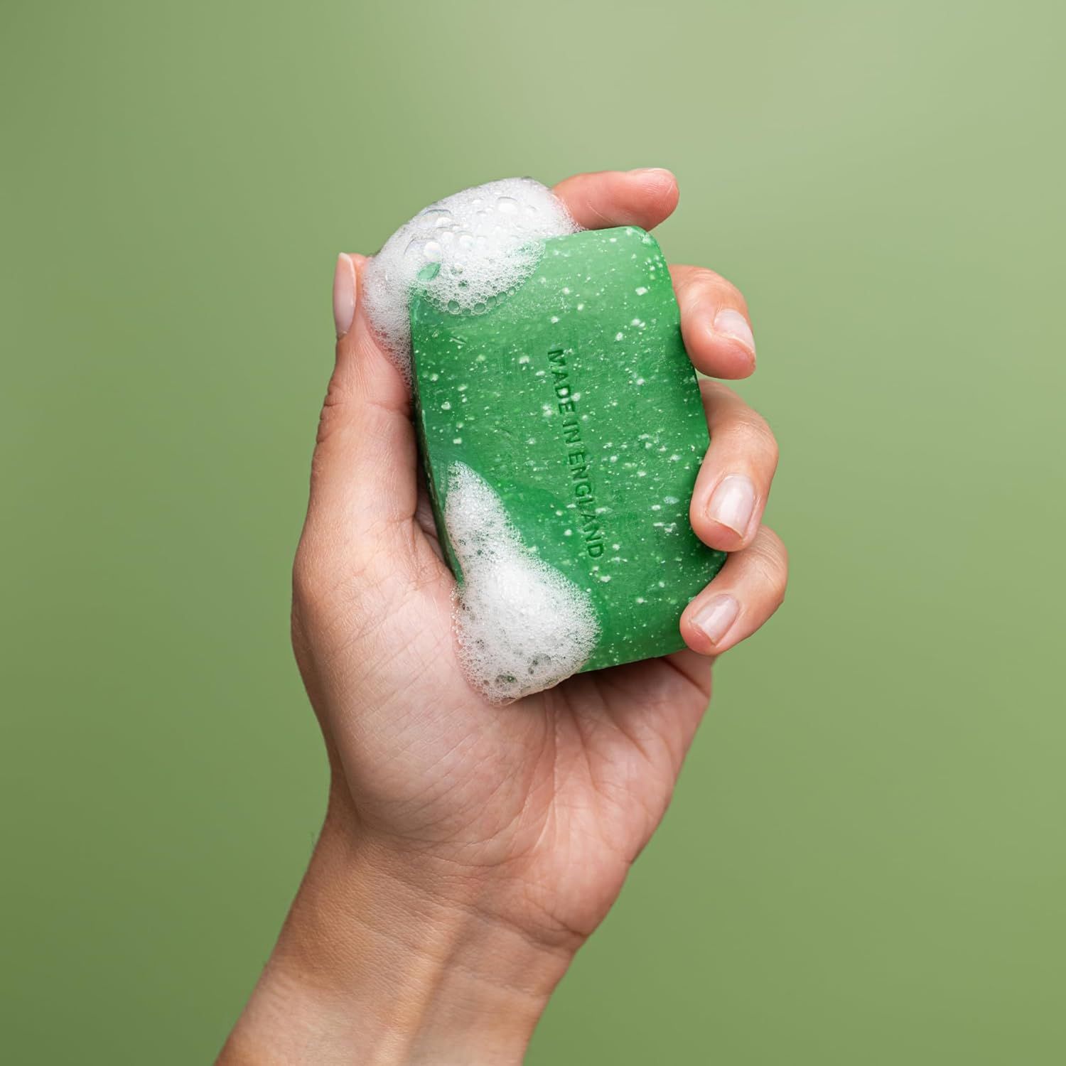 Mano che tiene sapone verde con schiuma. Scritta: Made in England.