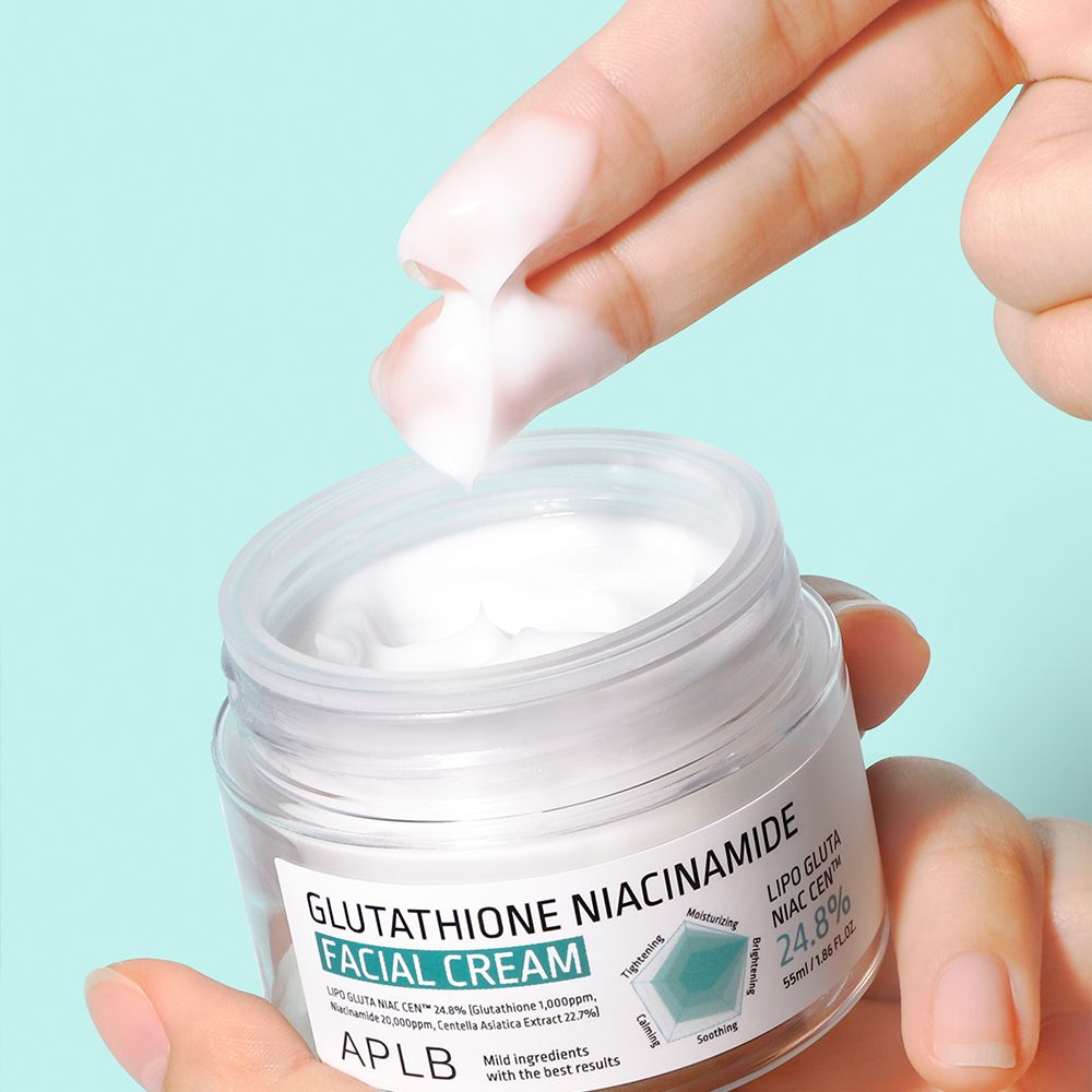 Una mano preleva crema viso APLB con glutatione e niacinamide da un vasetto in vetro.