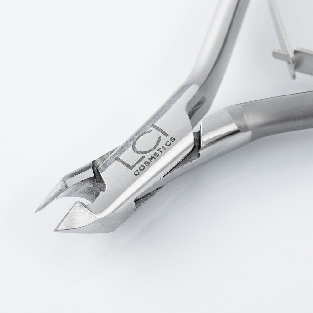 Primo piano della tronchesina. Metallo argentato, logo LCI Cosmetics. Taglio rotondo. Strumento professionale.
