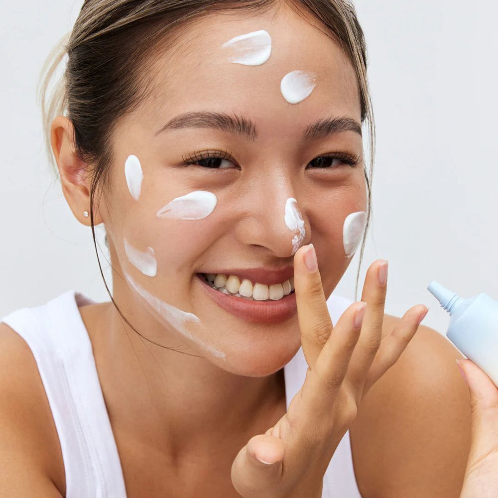 Donna che applica crema sul viso. Crema applicata sul viso. Tubo in mano.