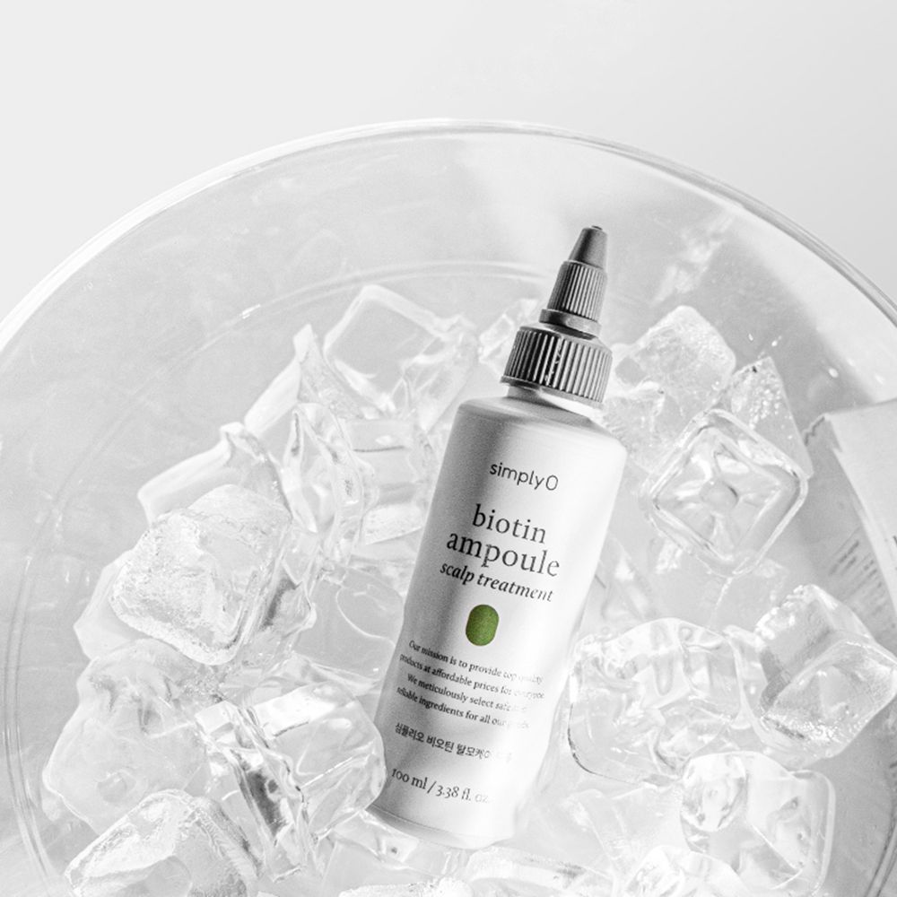 Un flacone con tappo nero in cubetti di ghiaccio. Scritta: Biotin Ampoule Scalp Treatment.