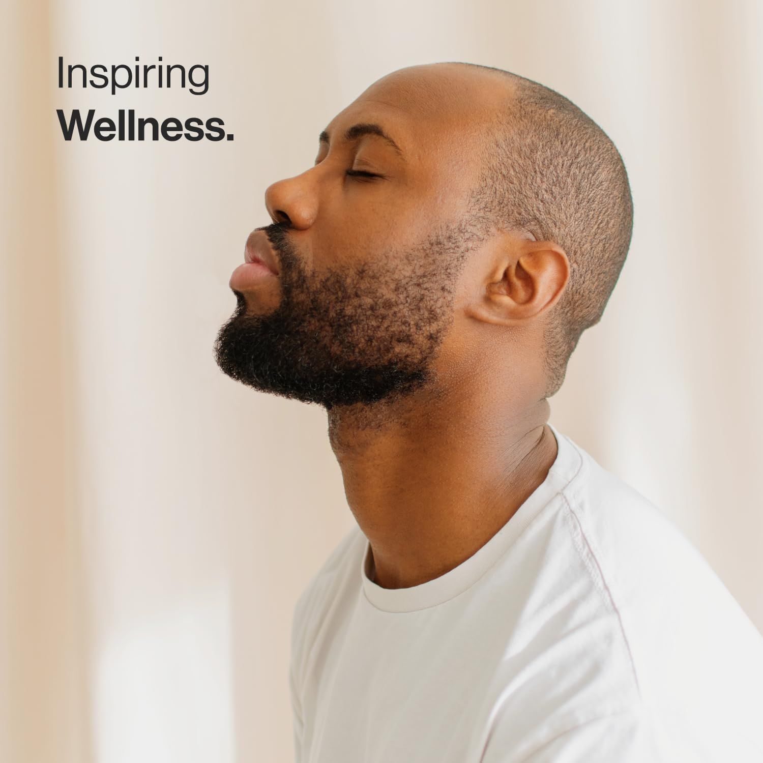 Un uomo con gli occhi chiusi. Indossa una maglietta bianca. Lo sfondo è chiaro.