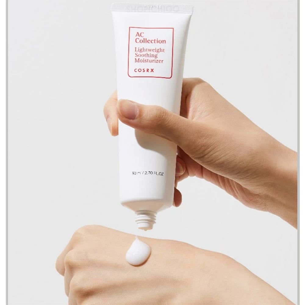 Tubo bianco, prodotto spremuto sulla mano. Etichetta rossa: AC Collection, Lightweight Soothing Moisturizer, COSRX. Crema sulla mano.