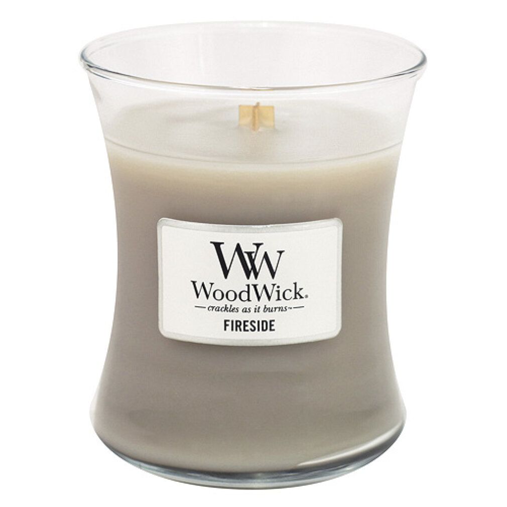 Candela grigia a forma di clessidra. Etichetta con logo WoodWick e testo: Fireside. Candela accesa.