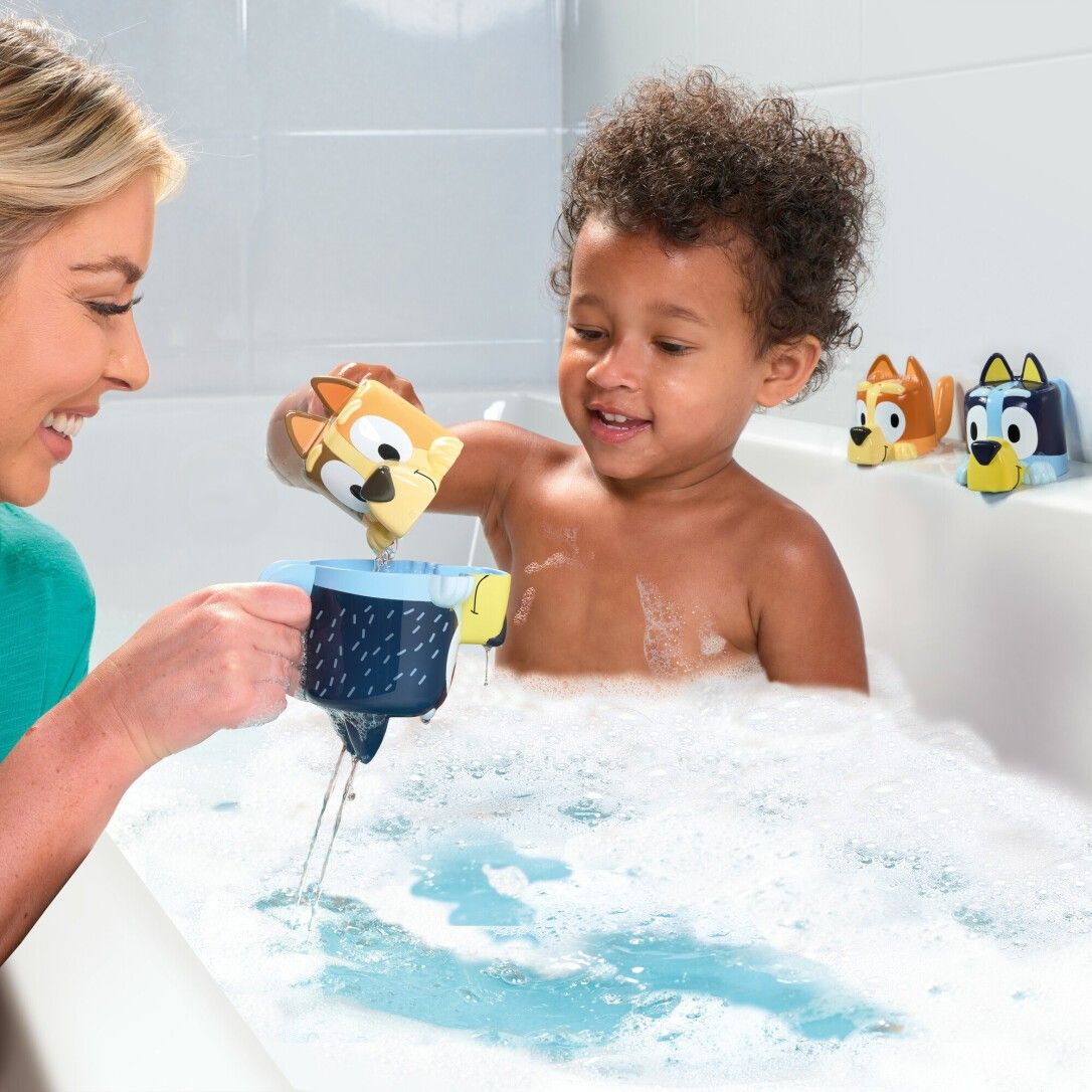 Bambino in vasca da bagno con giocattoli. Una donna versa acqua in un bicchiere. TOMY Bluey.