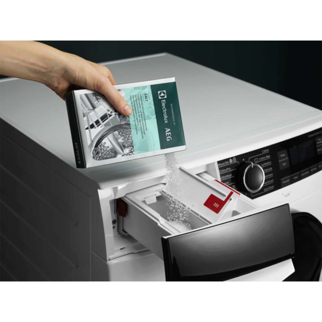 Una mano versa sale da una confezione Electrolux AEG nel vano detersivo di una lavatrice.