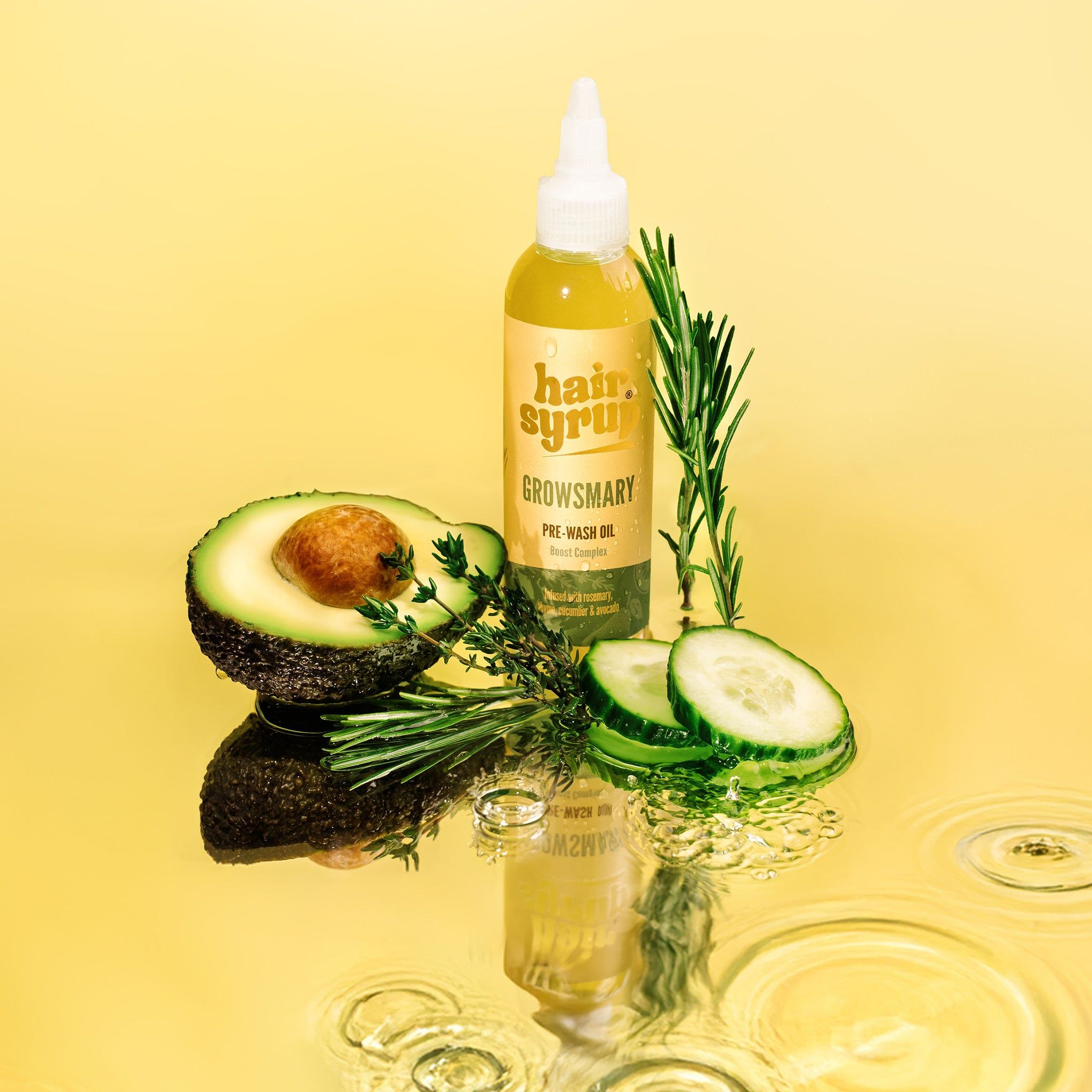 Bottiglia gialla « Hair Syrup Growsmary » con avocado, cetriolo, rosmarino e acqua. Su sfondo giallo.