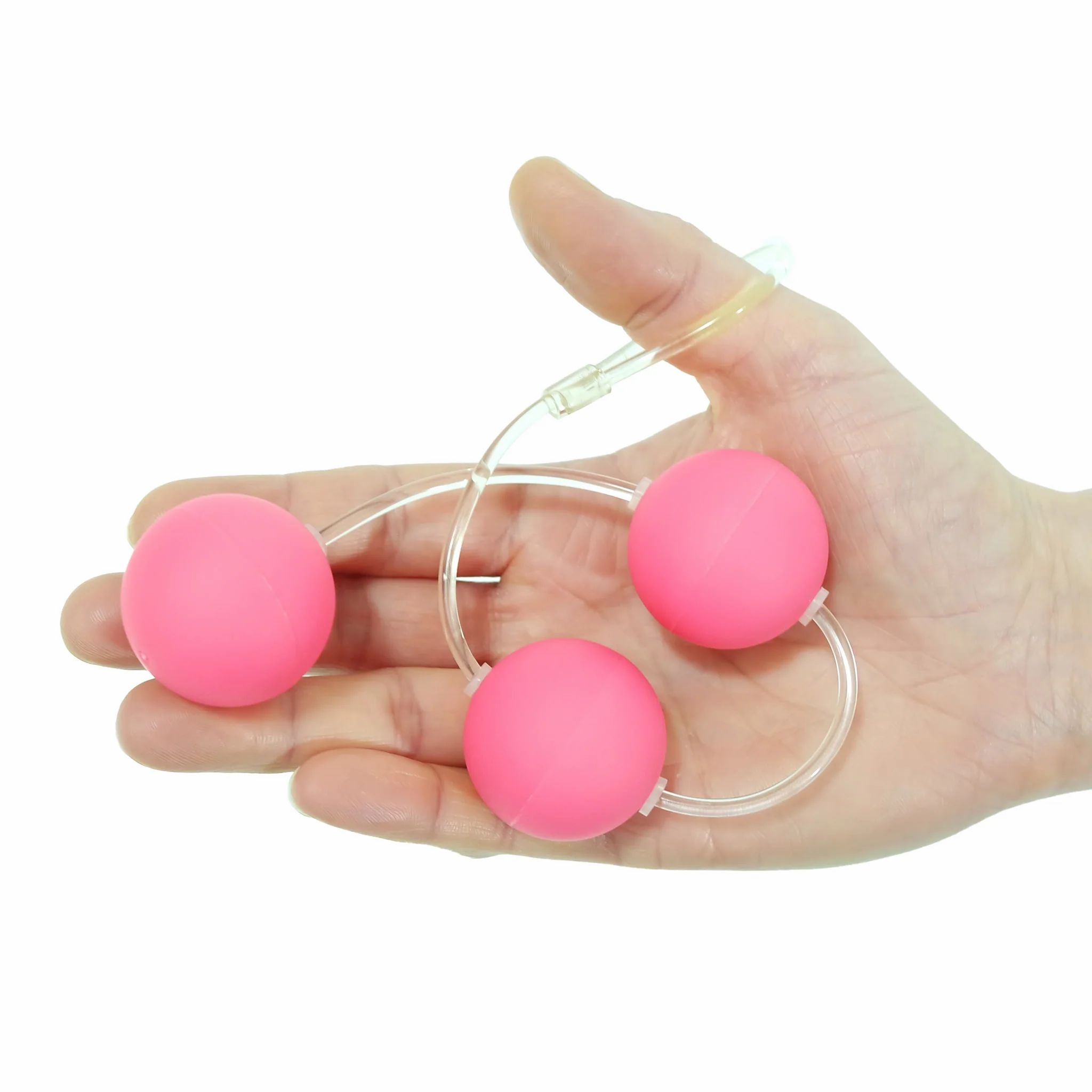 Tre sfere rosa su un anello trasparente, tenute da una mano.