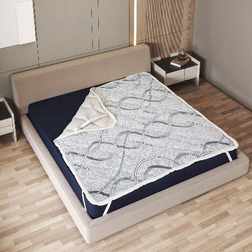 Coprimaterasso su un letto con copriletto scuro, con elastici agli angoli.