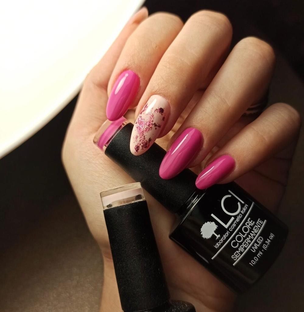 Mano con unghie fucsia smaltate. Flacone smalto: LCI, Colore Semipermanente.