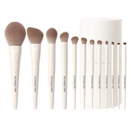 Un set di 10 pennelli per il trucco bianchi con setole beige e un contenitore rotondo bianco.