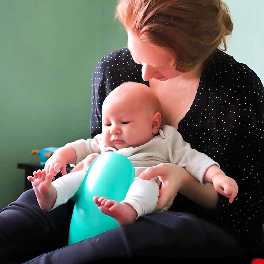 Madre tiene in braccio un bambino su un vasino turchese. Bambino seduto in grembo.
