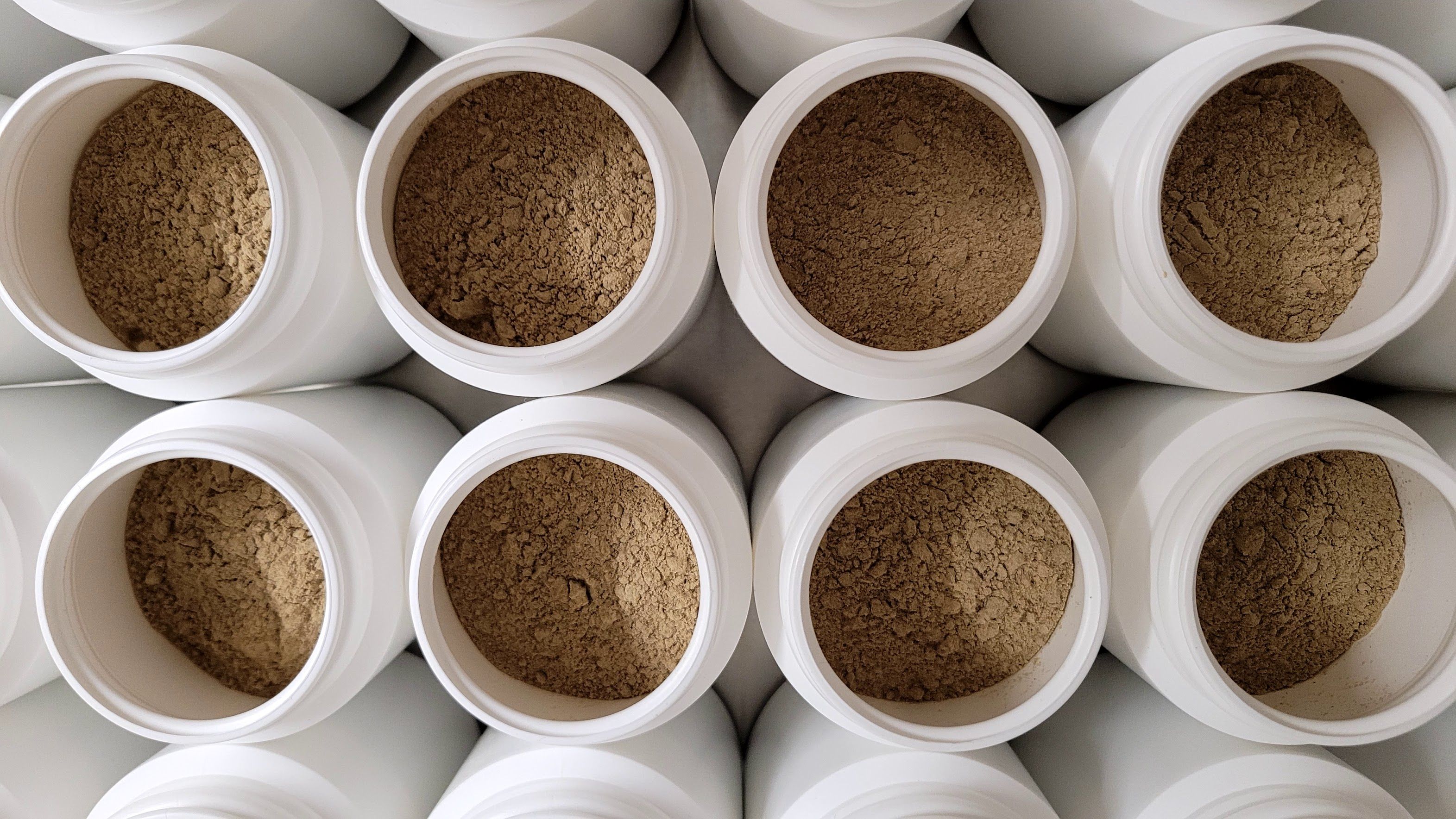Molti contenitori bianchi aperti con polvere marrone, probabilmente BEAUVITAL Hericium.