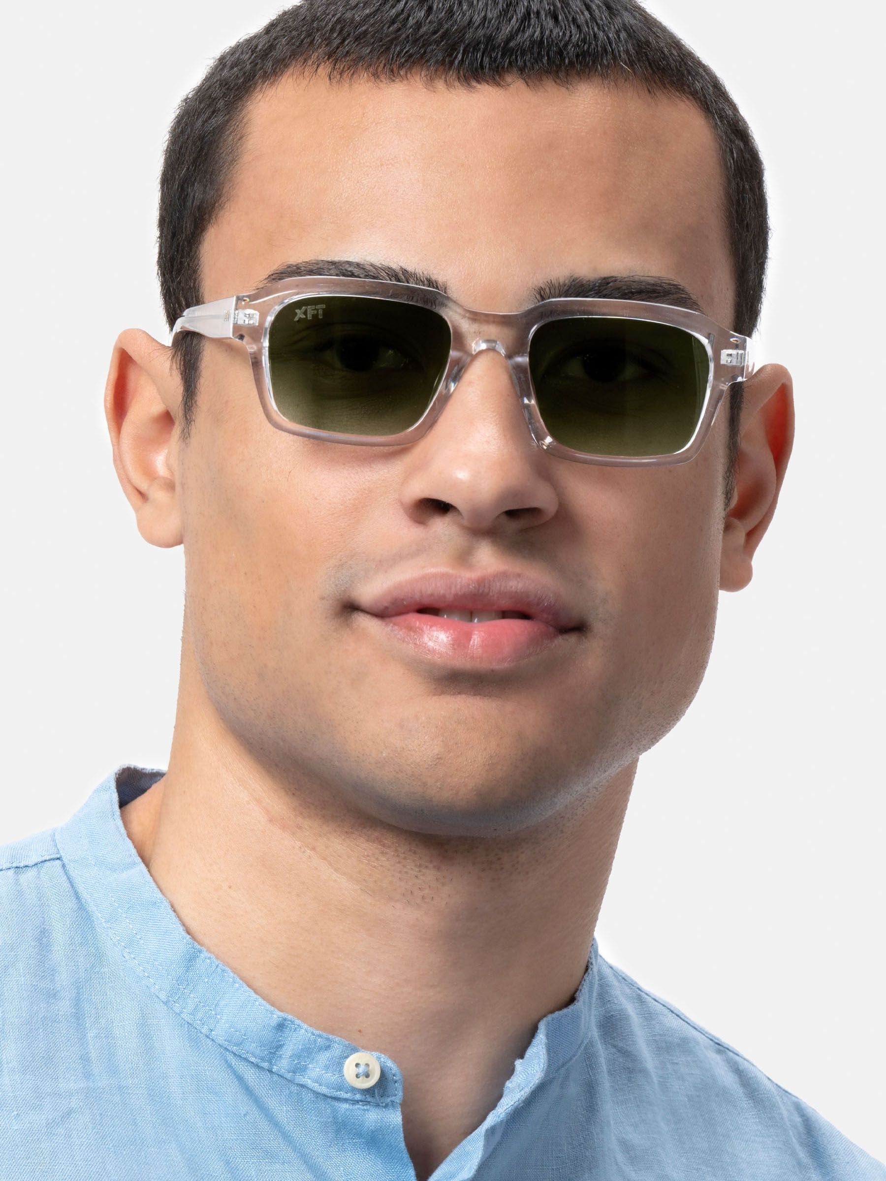 Uomo con occhiali da sole trasparenti con lenti verdi. Primo piano, forma rettangolare. Logo XFT sulla lente.