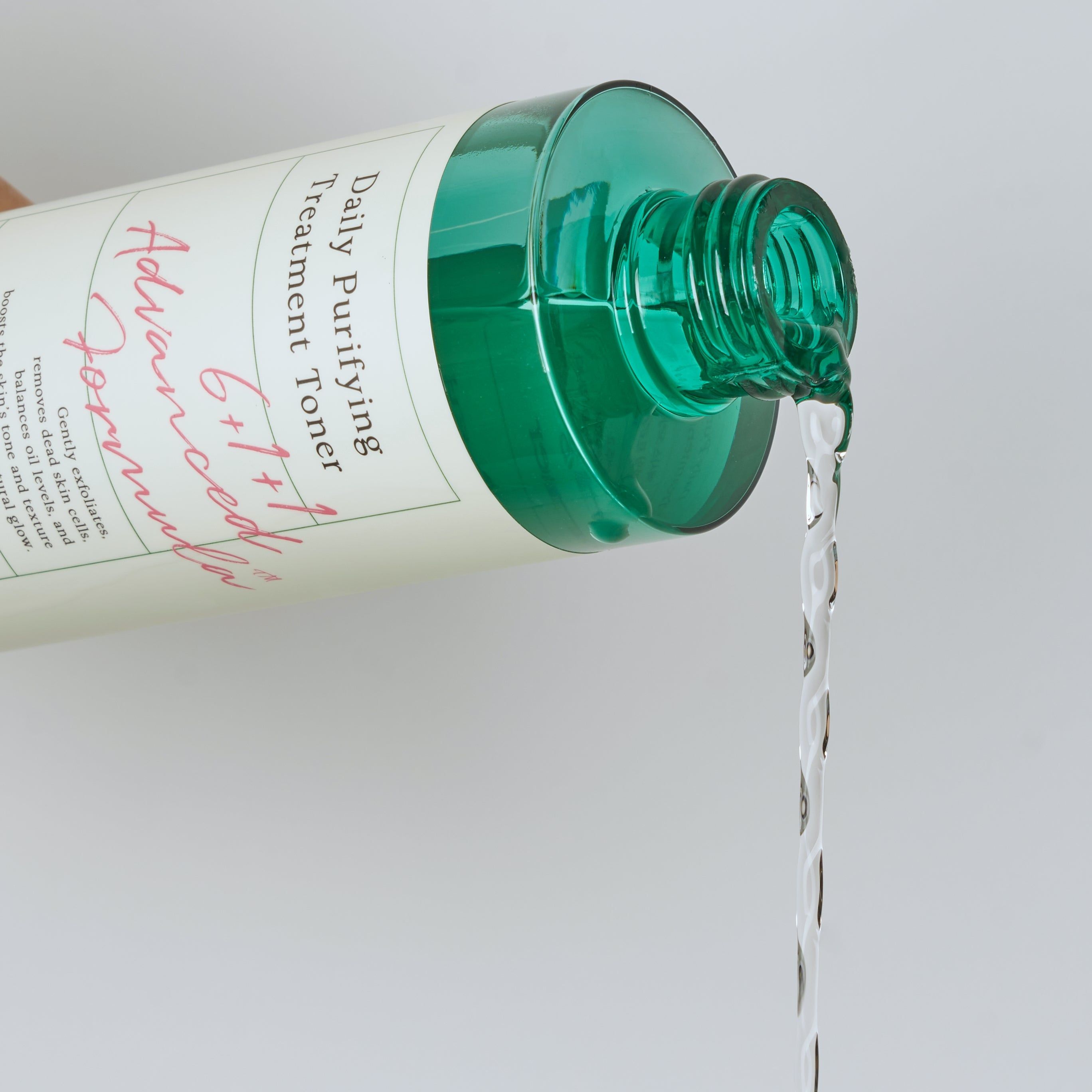 Toner versato da un flacone verde. Scritta: Daily Purifying Treatment Toner. Il liquido è trasparente.