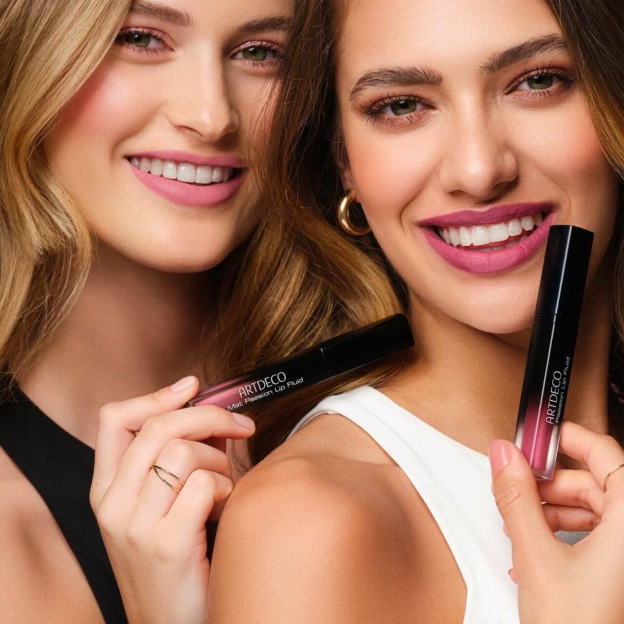 Due donne tengono Artdeco Mat Passion Lip Fluid. Entrambe sorridono. Prodotto in mano.