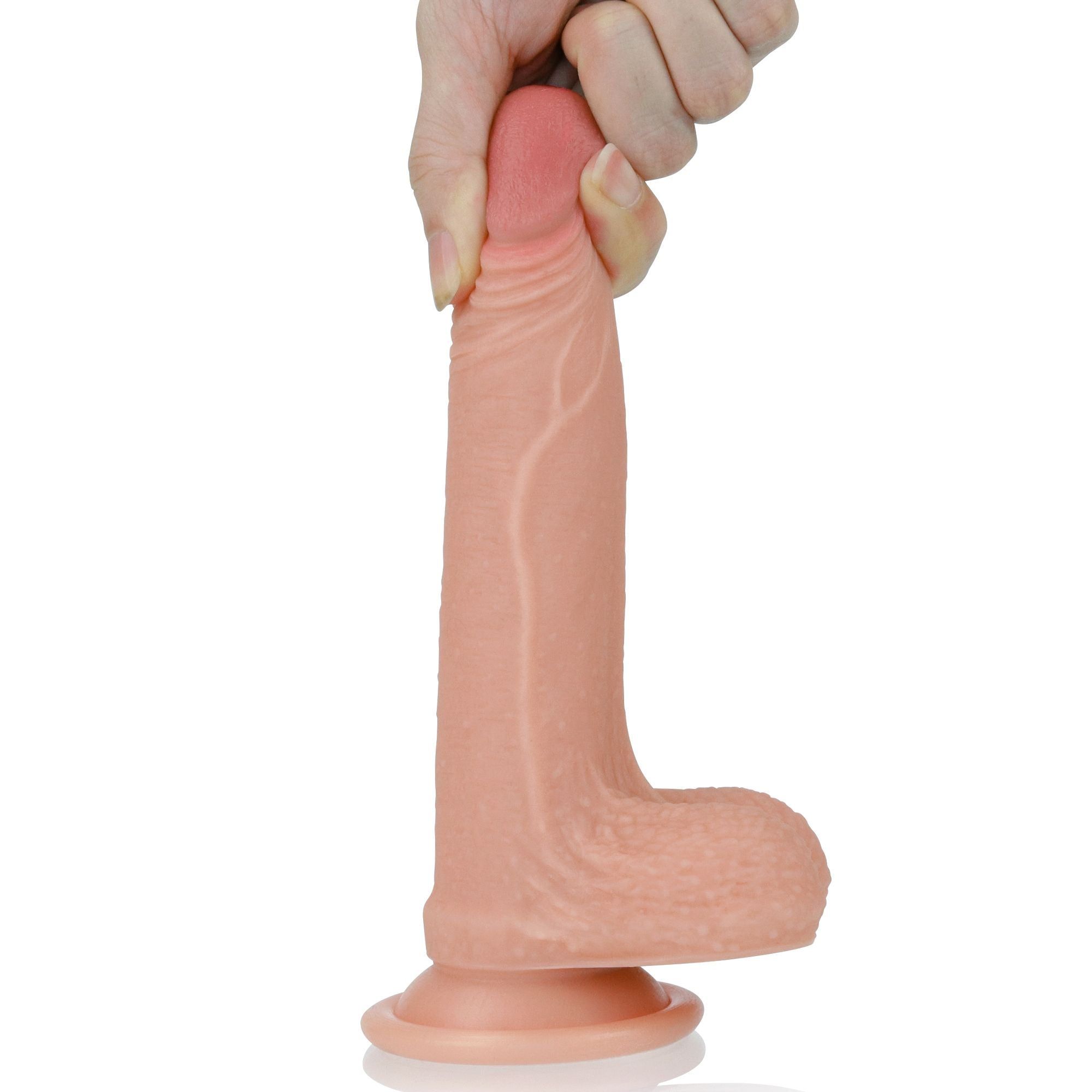 Dildo beige con punta rosa, tenuto da una mano. Su sfondo bianco.