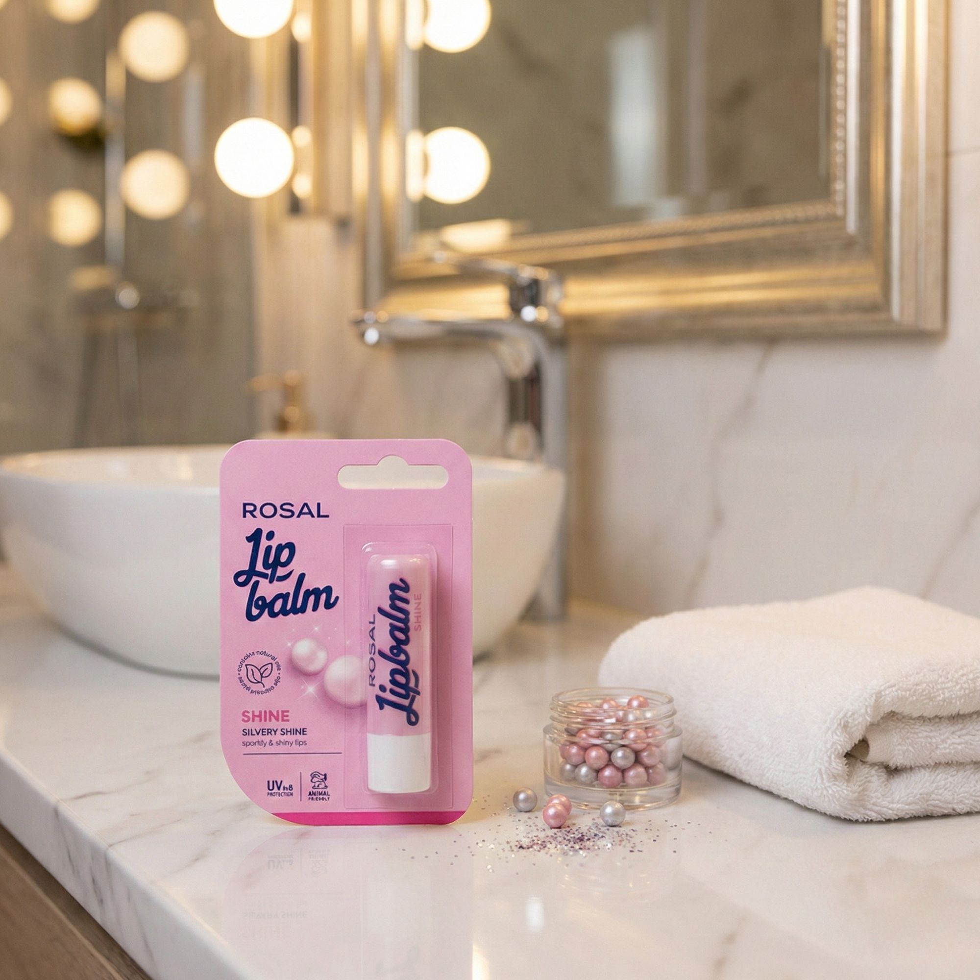 Lip Balm in confezione rosa. Testo: ROSAL, Lip balm, Shine, Silvery Shine, protezione UV, cruelty-free. Su marmo, accanto a perle.