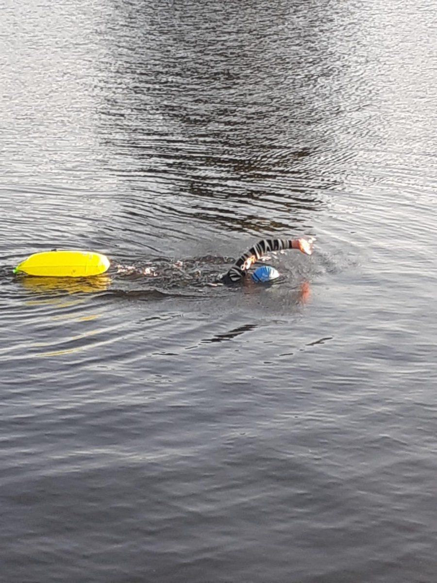 Persona che nuota in acqua, collegata a boa gialla. Boa che galleggia sull'acqua.