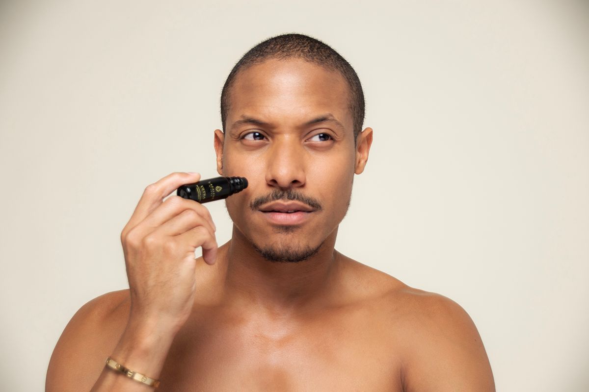 Un uomo tiene un flacone Lagalene Milano Ultra Intensive Care con applicatore roll-on vicino al suo viso. Sul flacone è scritto "ULTRA INTENSIVE TREATMENT".