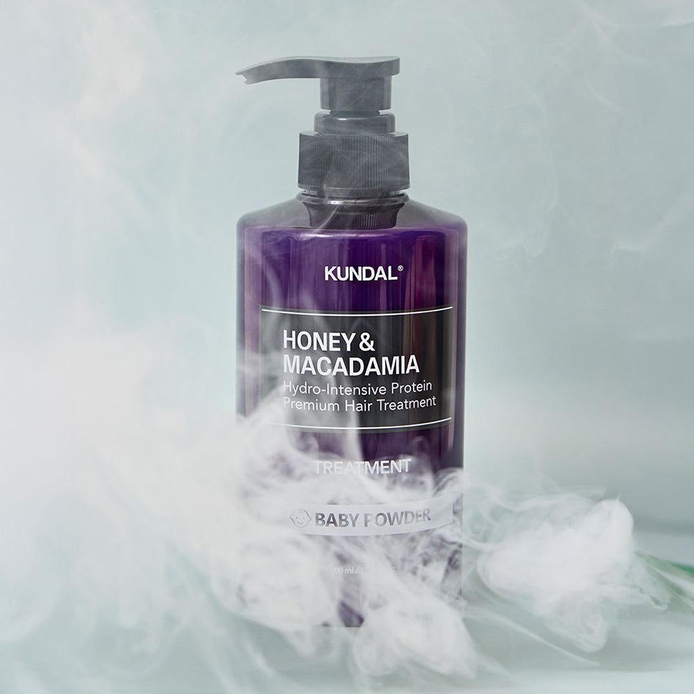 KUNDAL Honey & Macadamia Protein Treatment in flacone viola, circondato da fumo.