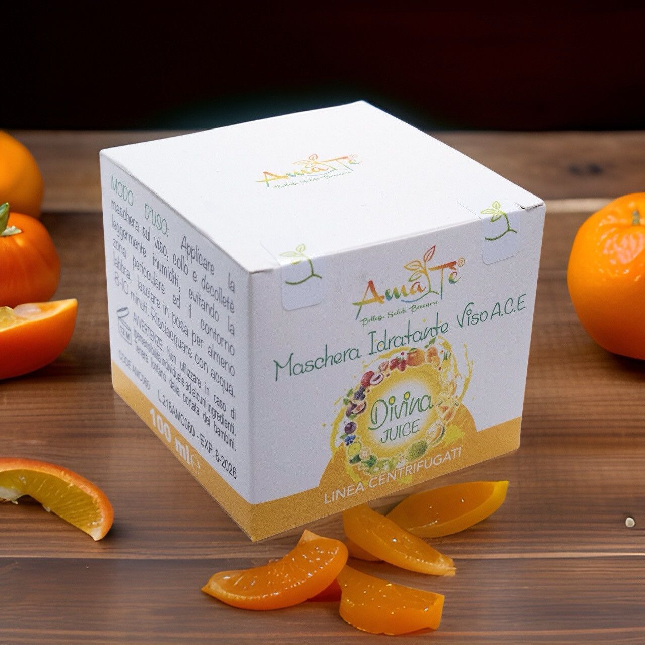 Confezione prodotto su fondo legno con arance. Scritta: Maschera Idratante Viso A.C.E. Divina Juice. Logo Amatè.