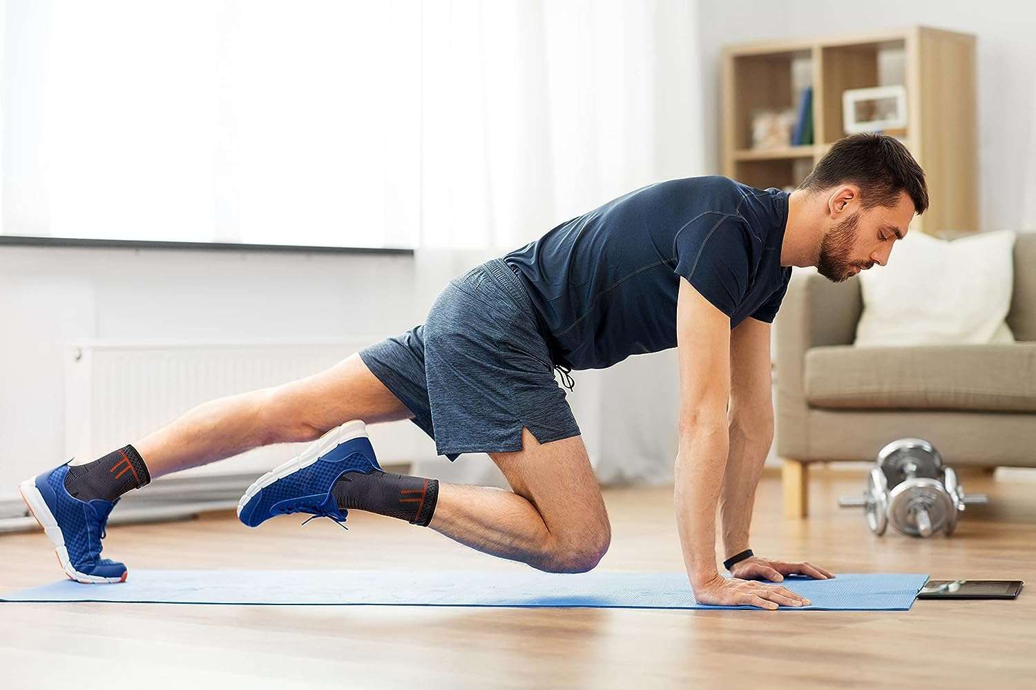 Uomo che si allena su un tappetino. Indossa cavigliere nere e pantaloncini blu. Bende con dettagli rossi.