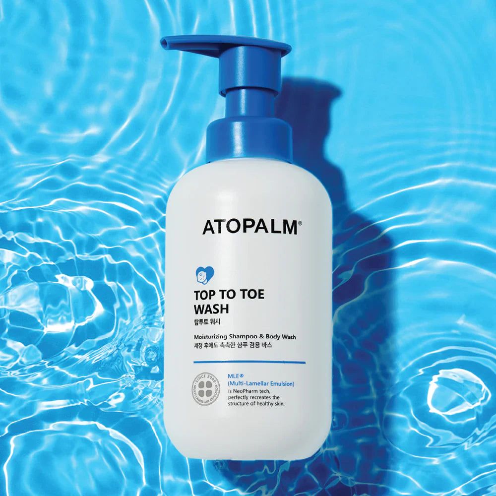 Flacone bianco con erogatore blu. Scritta: ATOPALM TOP TO TOE WASH. Sfondo: texture acqua.