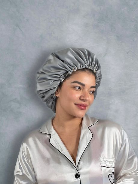 Donna con cuffia in seta grigia. Indossa anche una camicia da notte in seta bianca con bordi neri.