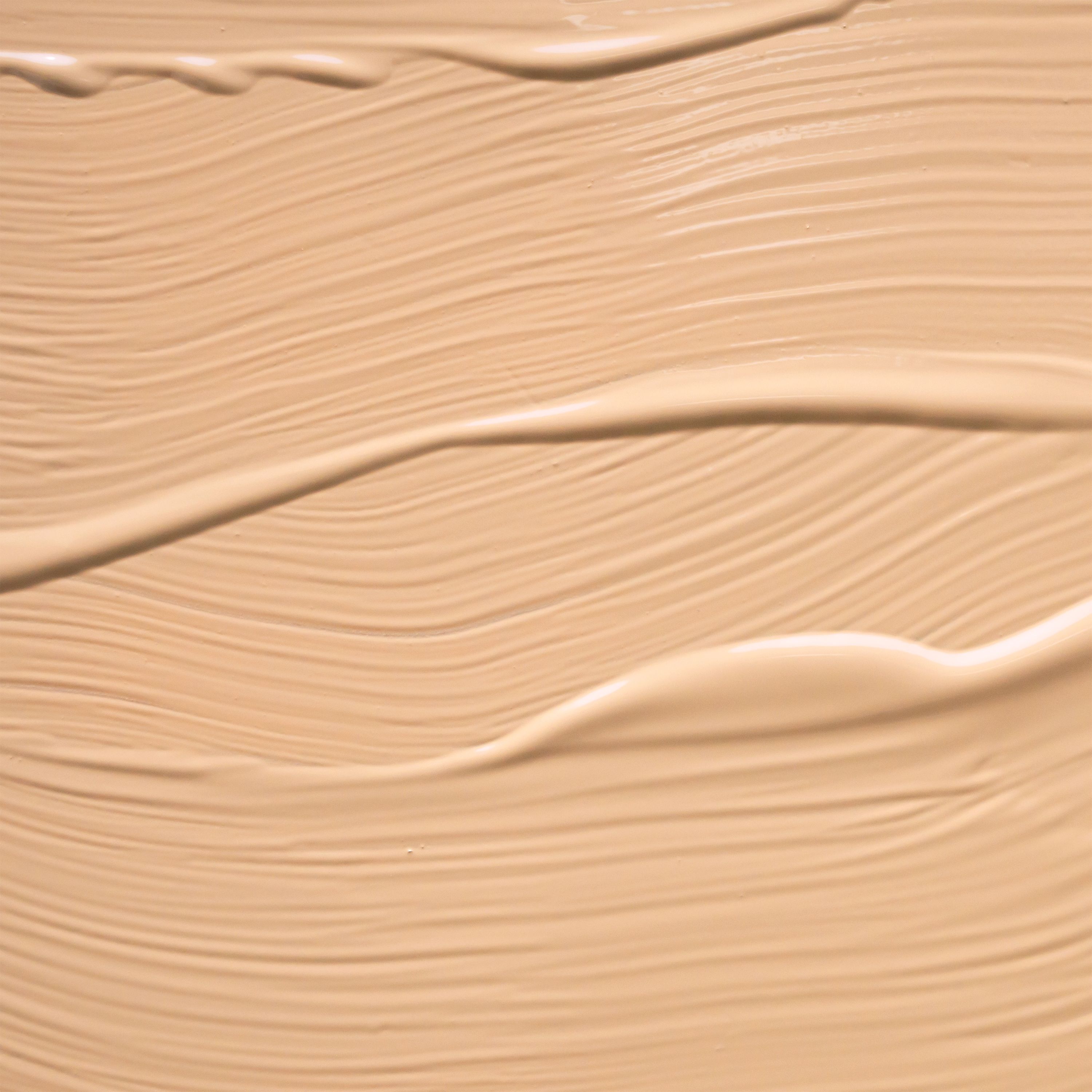 Primo piano di una crema liquida color beige chiaro con sottili pennellate.