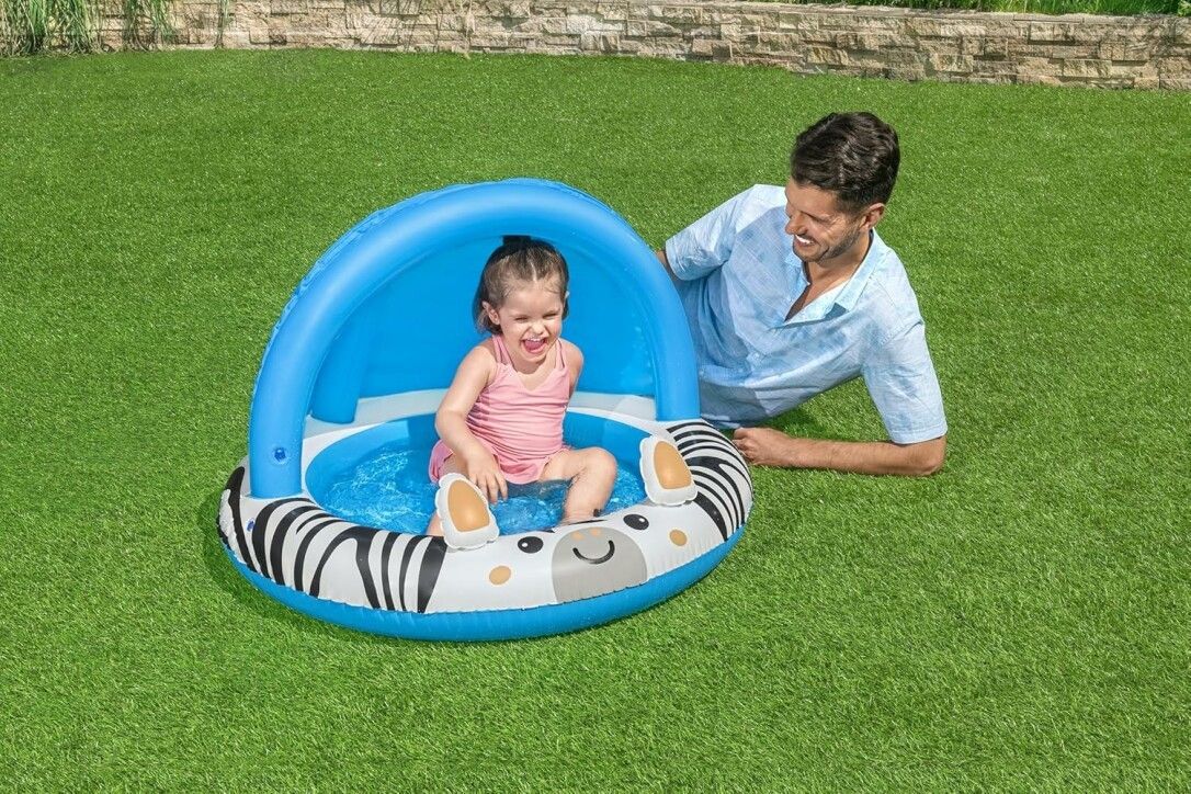 Piscina per bambini con parasole blu. Design zebrato, bambino dentro e uomo accanto.