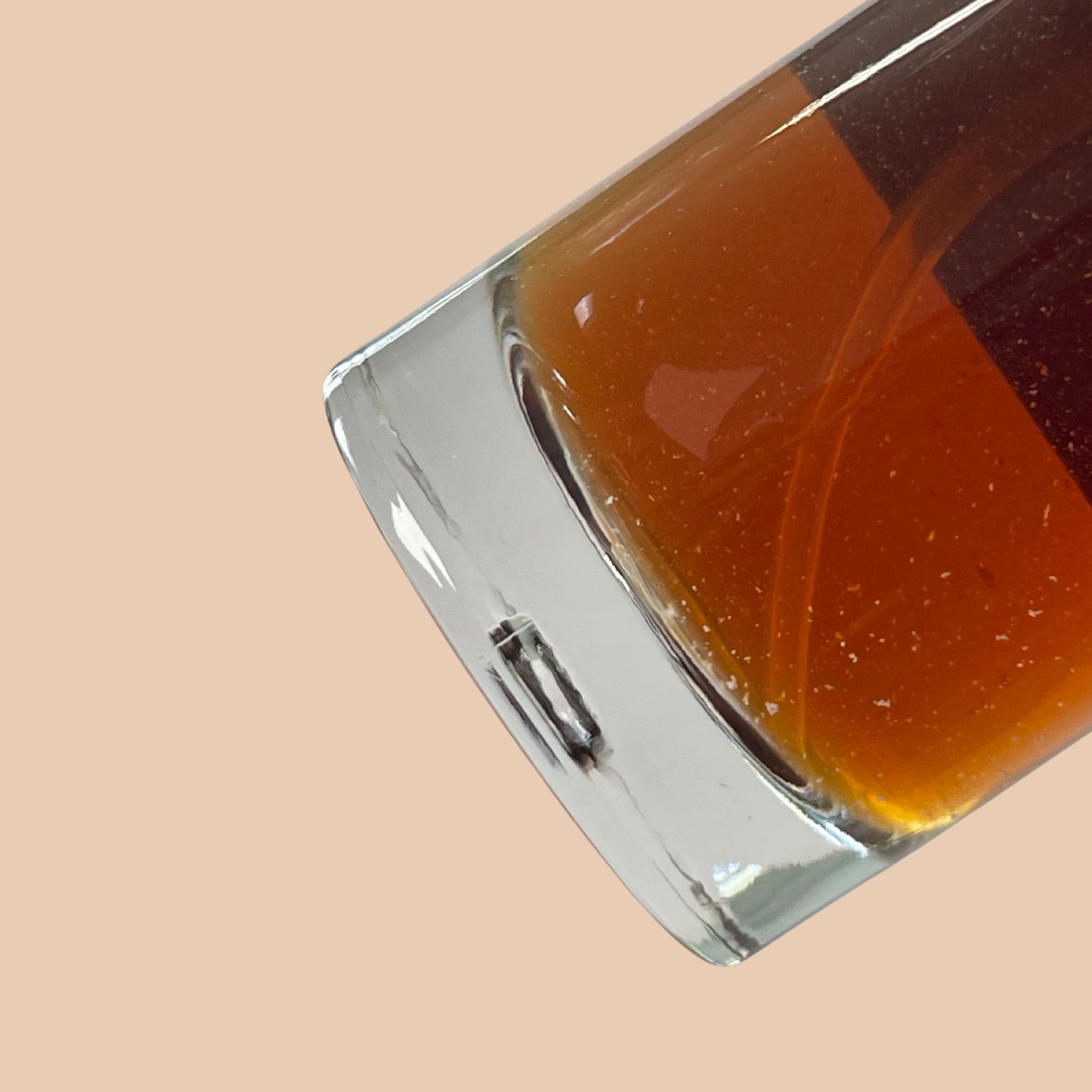 Primo piano di un flacone in vetro con liquido. Forma angolare.