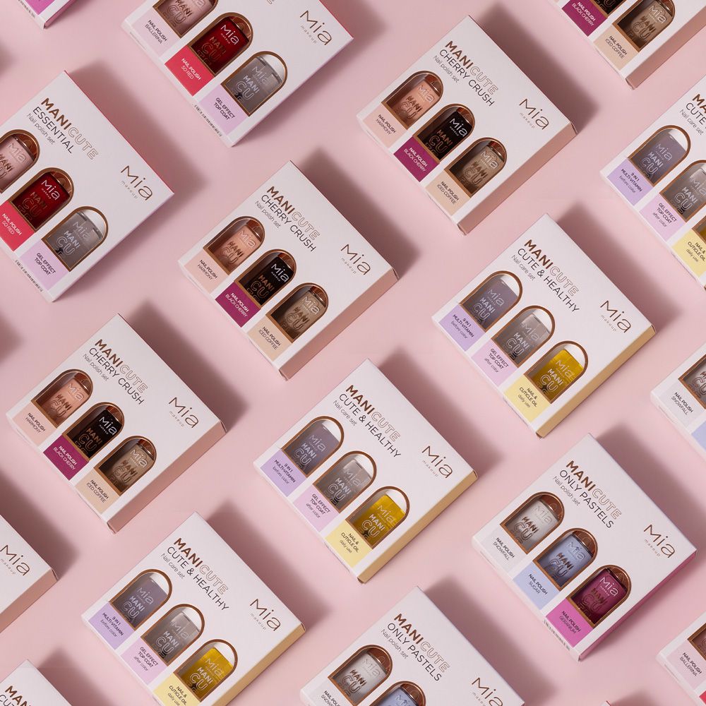 Diversi set smalti Mia Makeup Manicute. Vari set, tra cui Only Pastels. Sfondo rosa. Scatole con tre flaconi.