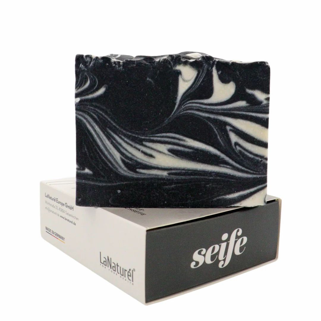 Sapone nero con vortici bianchi su una scatola. Sulla scatola c'è scritto "seife".