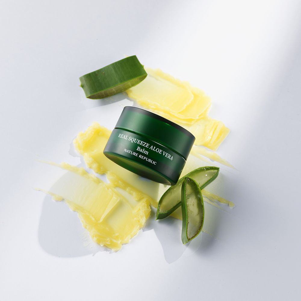 Vasetto verde con balsamo giallo, foglie e strisce di aloe vera. Scritta: Real Squeeze Aloe Vera.