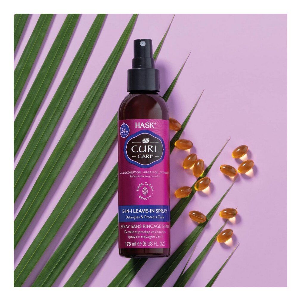Flacone spray marrone con erogatore nero. Etichetta con nome e testo del prodotto. Su sfondo viola con foglie e capsule.