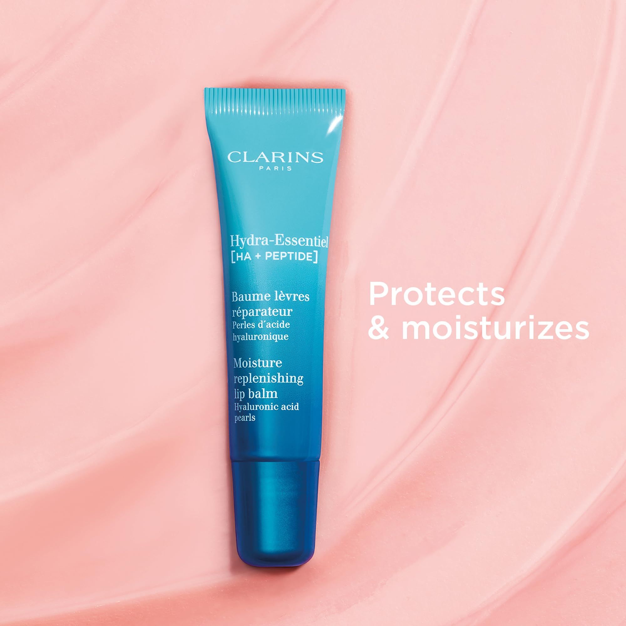 Tubo di balsamo labbra Clarins Hydra-Essentiel su sfondo rosa. Testo: Hydra-Essentiel, Baume lèvres réparateur, Moisture replenishing lip balm.