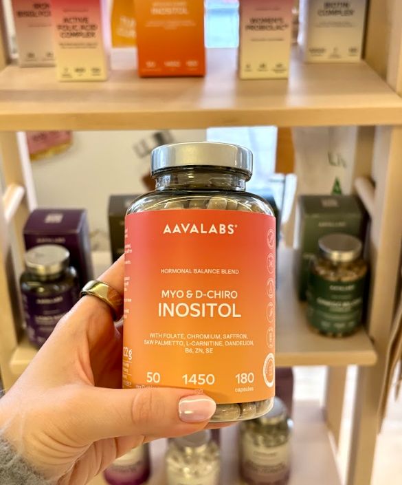 Mano che tiene un flacone Aavalabs Myo- & D-Chiro Inositol su uno scaffale.