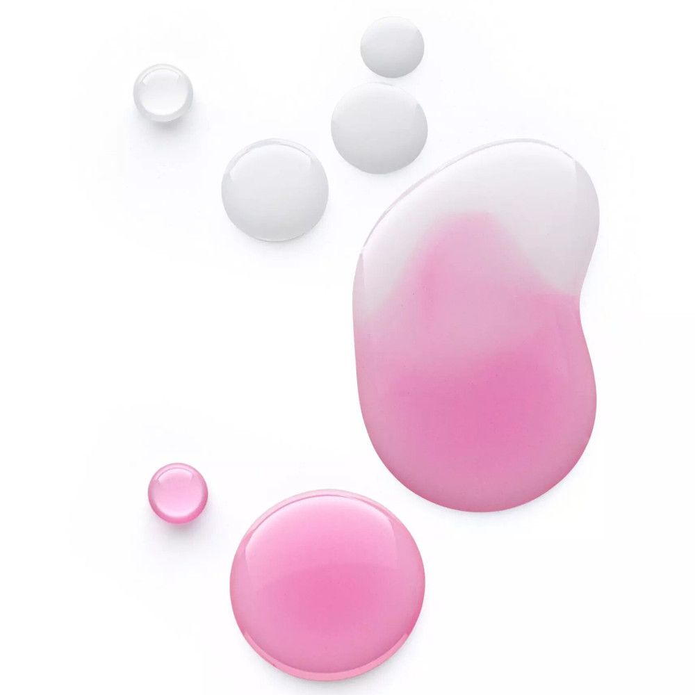 Gocce di olio per labbra rosa su sfondo bianco. Diverse dimensioni e forme. Alcune gocce sono trasparenti.