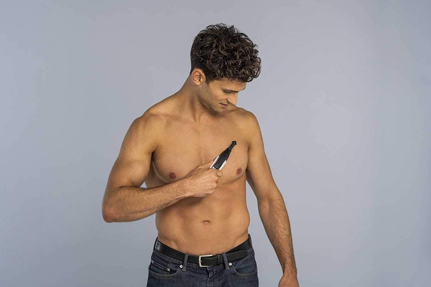 Uomo che si rade con un tagliacapelli. L'uomo è a torso nudo. Il dispositivo è nero, argento e bianco.